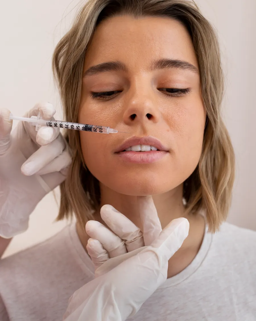 Ärztin stützt das Kinn und setzt die Unterspritzung an der Lippe