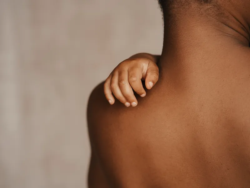 Kinderhand liegt auf der Schulter eines Erwachsenen vor beigem Hintergrund